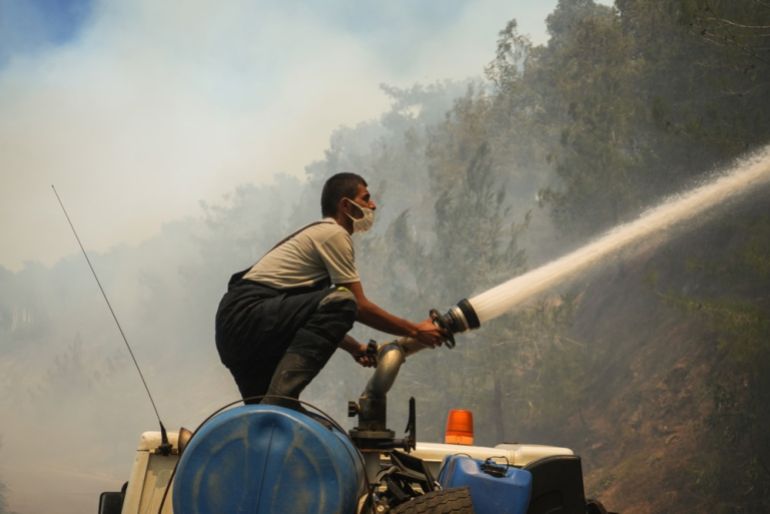 Un miembro de Sirian Emergency Services lucha contra las llamas en el sitio de un incendio en el campo de Qastal Maaf do Campo de Latakia
