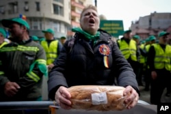 ARCHIVO - Una mujer sostiene pan durante una protesta de agricultores en Bucarest, Rumania, el 7 de abril de 2023. Polonia, Hungría, Eslovaquia y Bulgaria prohibieron las exportaciones de alimentos de Ucrania para proteger sus propios mercados.  Dicen que no pueden competir con precios bajos en Ucrania.