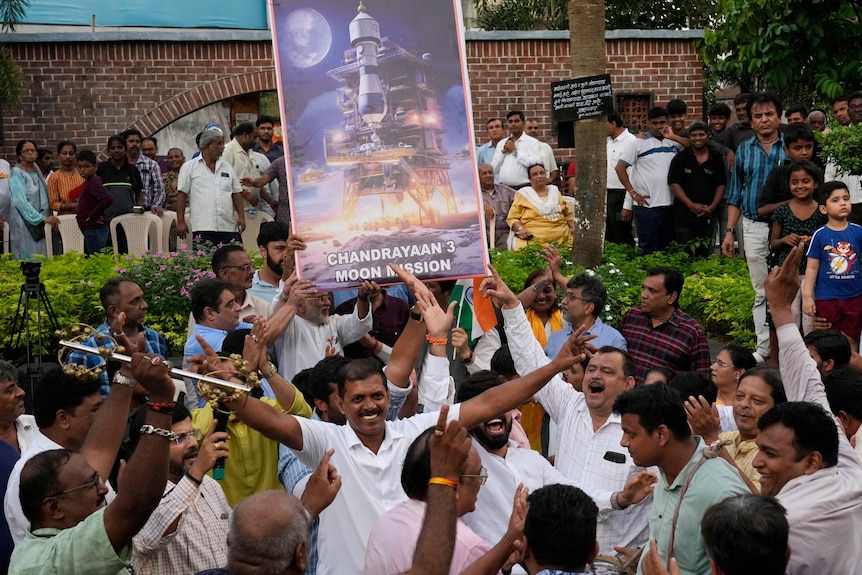 La gente celebra mientras ve una transmisión en vivo del alunizaje en la India. 