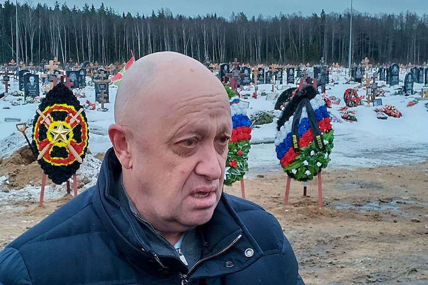 Un primer plano de un hombre calvo que llevaba un suéter mirando hacia otro lado de la cámara en un campo nevado.