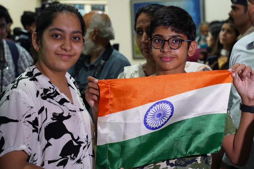 Una mujer junto a un niño que sostiene la bandera nacional india.