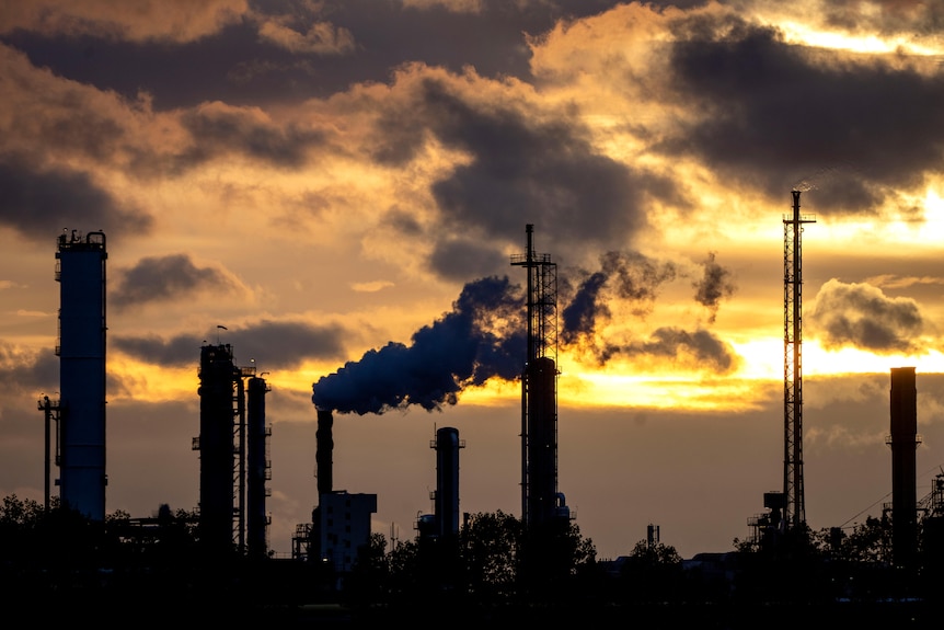 La contaminación surge de una planta química industrial que se destaca contra el cielo nocturno. 