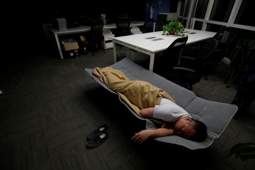 Un hombre durmiendo en la cama de la oficina.