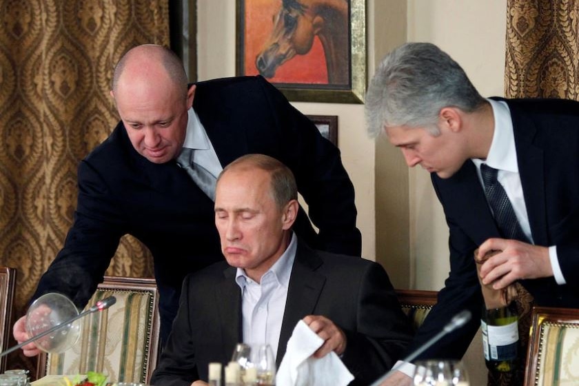 Dos hombres se paran frente al primer ministro ruso, Vladimir Putin, cuando está a punto de empezar a comer.