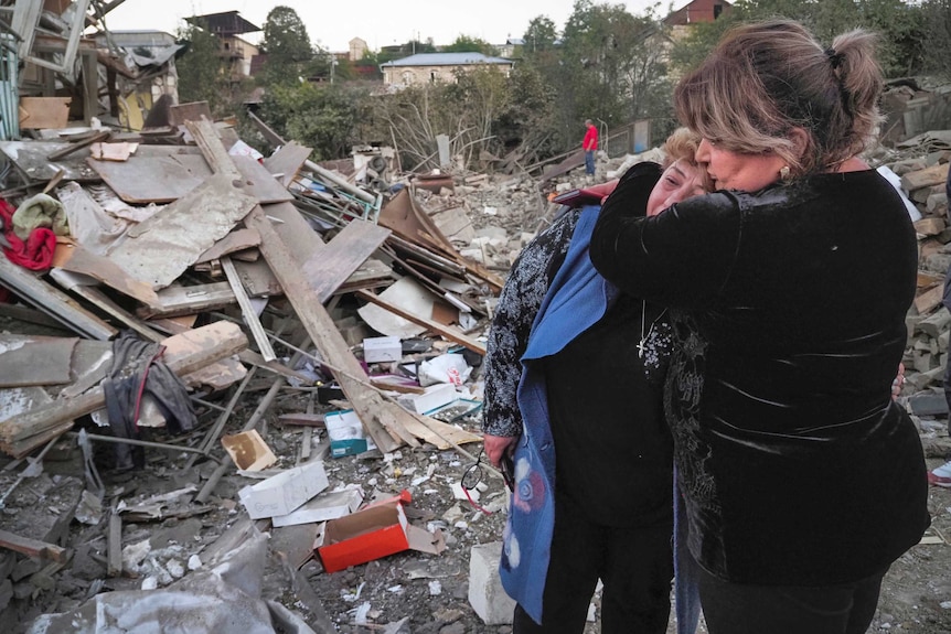 Un vecino consuela a la ama de casa Lida Sarksyan cerca de su casa, que fue destruida por los bombardeos de artillería azerbaiyanos.