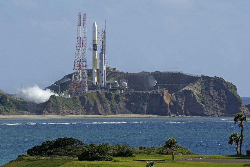 Un vehículo de lanzamiento de cohetes espaciales en una isla rocosa, la foto está tomada desde tierra firme a través del agua.