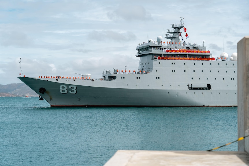 Un barco gris de la Armada en aguas azules poco profundas en un día nublado