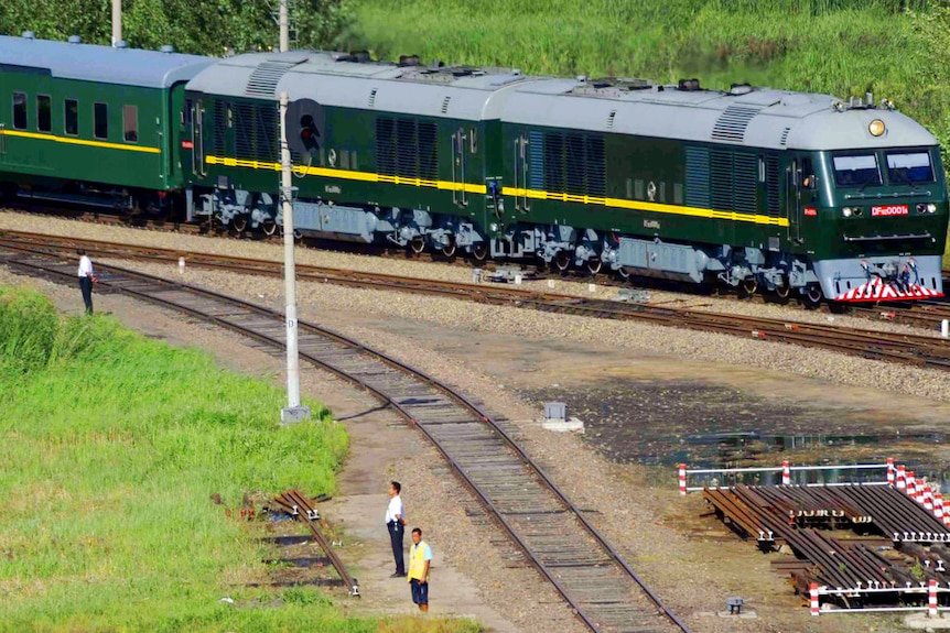 Un tren blindado verde que viaja por una vía a través de campos verdes en China
