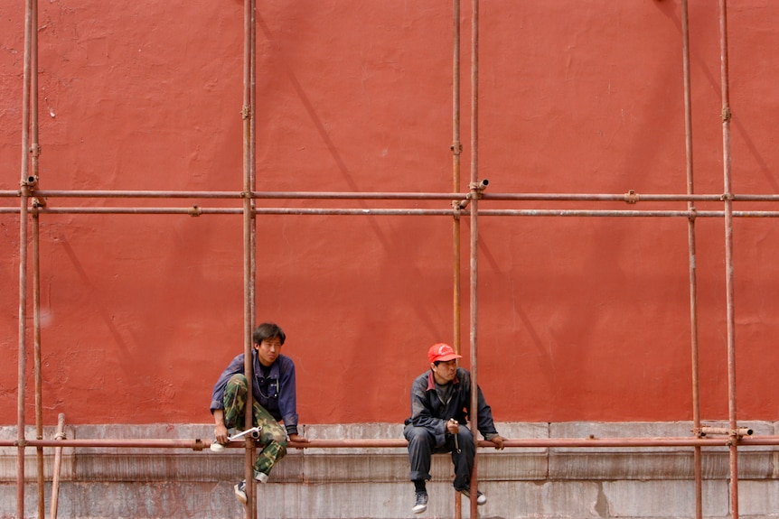 Trabajadores sentados en andamios en una obra de construcción en la Ciudad Prohibida de Beijing