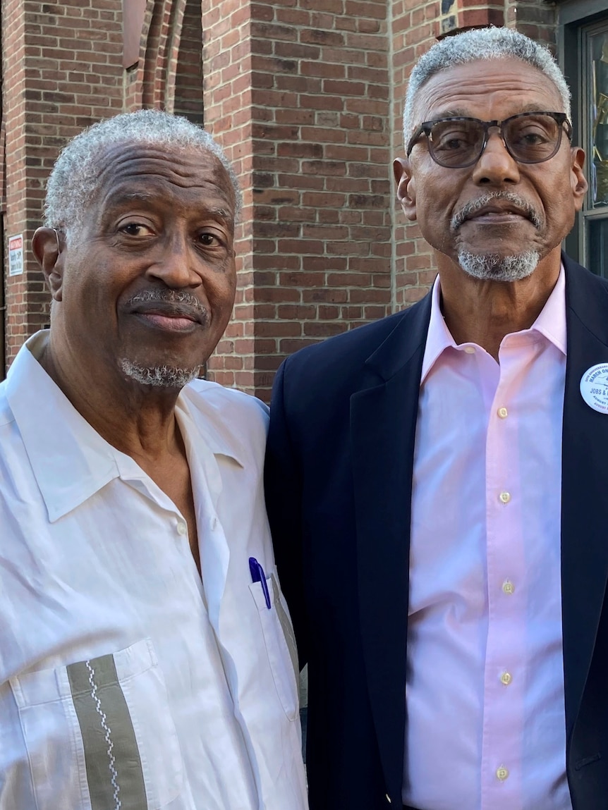 Dos hombres afroamericanos mayores miran a la cámara. 