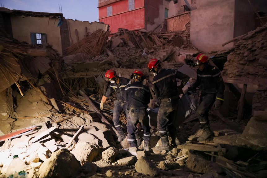 Los trabajadores de emergencia trabajan entre polvo y escombros. 