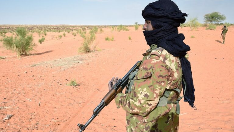 Man wearing holds gun in desert