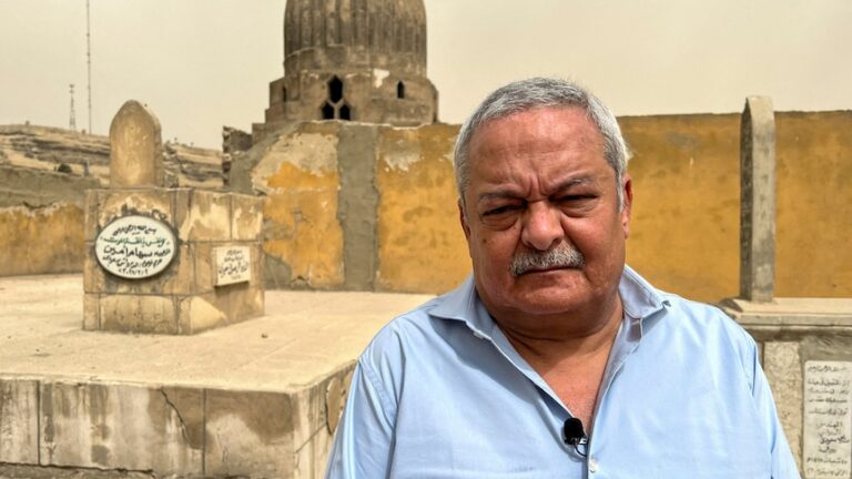 frowning man stands in front of older building