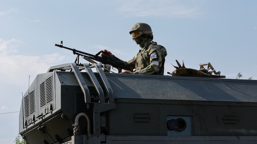 Man with gun stands on war tank