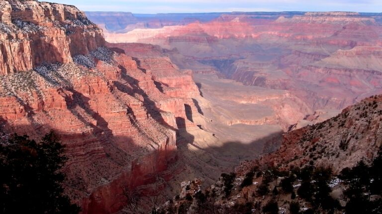 A pile of red coloured rocks with trees surrounding them.