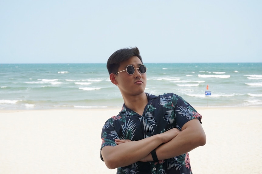 Un hombre con gafas de sol parado en la playa.