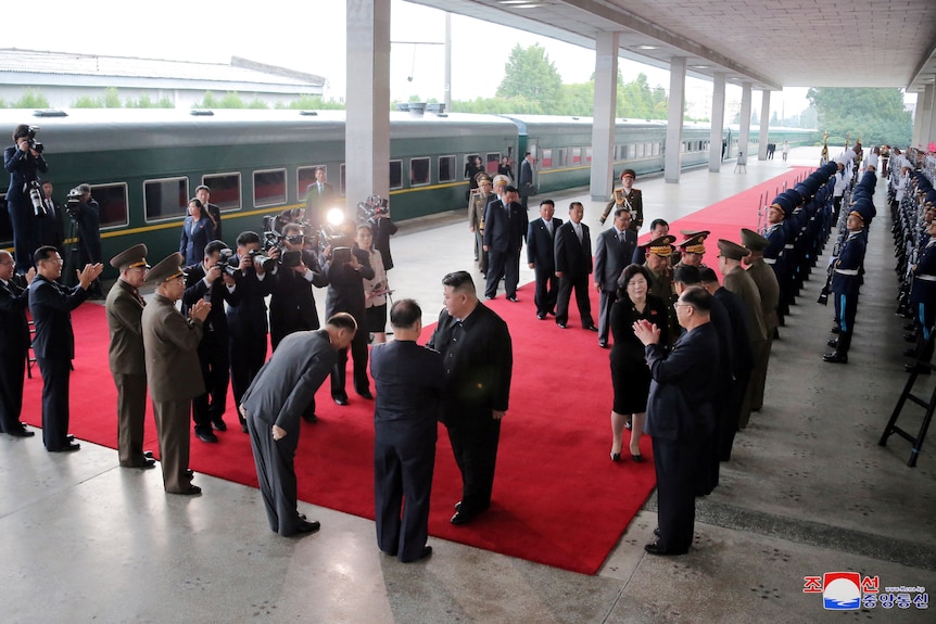 Kim Jong Un y decenas de empleados en un andén de ferrocarril. 