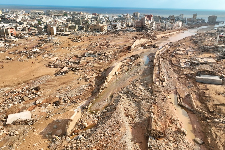 Una fotografía aérea de una ciudad costera histórica con muchos edificios destruidos y una gran división en el medio, despejada por una inundación.