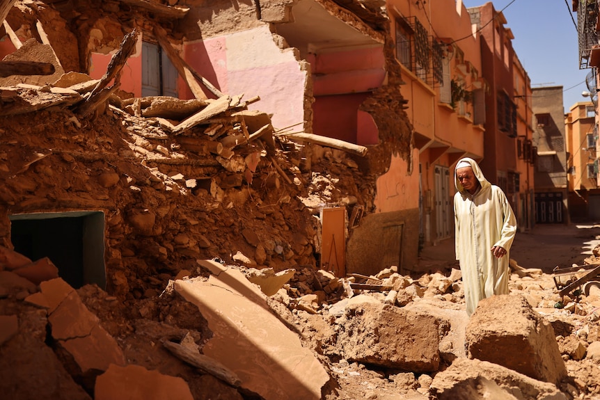 Un hombre se para frente a los escombros de una casa derrumbada 