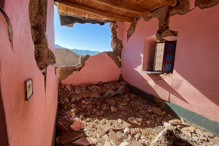 Una casa con paredes rosas tiene escombros por todo el piso.