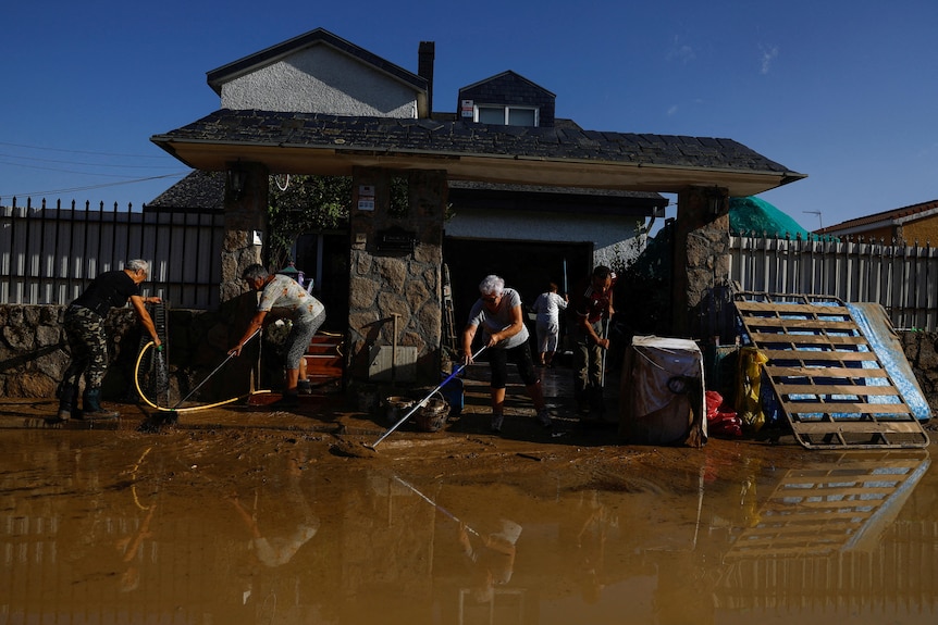 Una familia saca agua turbia de su casa 