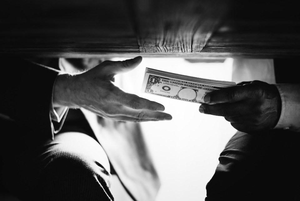 manos pasando dinero debajo mesa corrupcion soborno