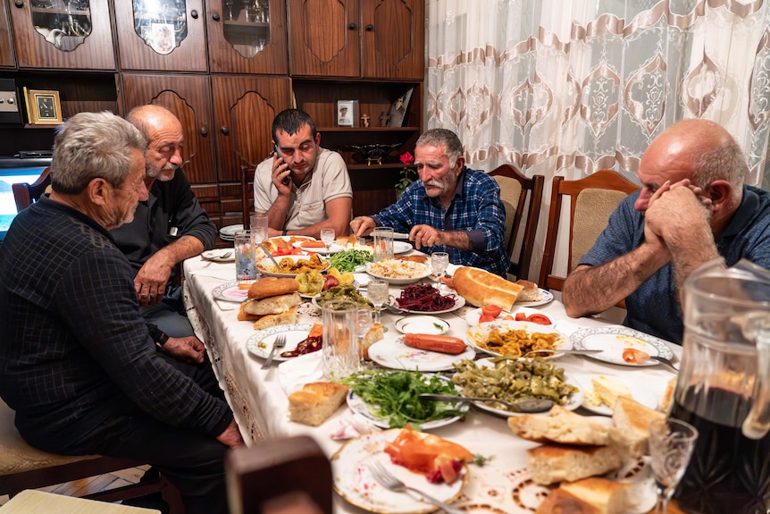 Un grupo de personas están sentadas alrededor de una mesa con platos llenos de comida.