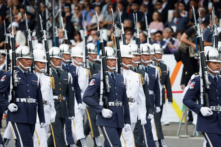 Guardias ceremoniales marchando en la ceremonia de inauguración.  Algunos tienen uniformes blancos y otros tienen uniformes azules.  Llevan rifles con bayonetas.