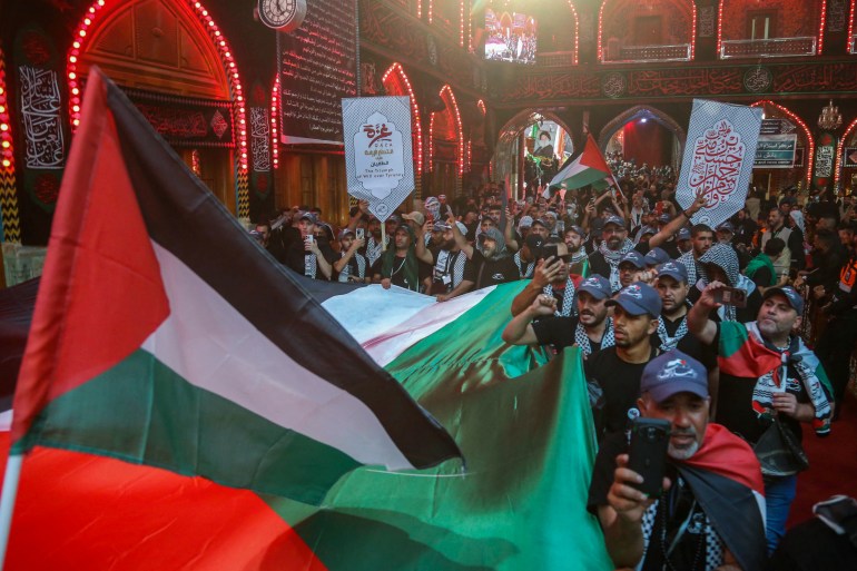 Los devotos izan banderas palestinas y usan pañuelos tradicionales keffiyeh palestinos para expresar su apoyo a Gaza, mientras participan en un ritual de luto en el santuario del Imam Abu Al-Fadl al-Abbas en Karbala, Irak, el 24 de agosto de 2024, como peregrinos musulmanes chiítas. se reúnen en la ciudad santuario para las celebraciones de Arbain que marcan el final del período de luto de 40 días por el asesinato en el siglo VII del nieto del profeta Mahoma, el Imam Hussein Bin Ali (Foto de Mohammed SAWAF/AFP).