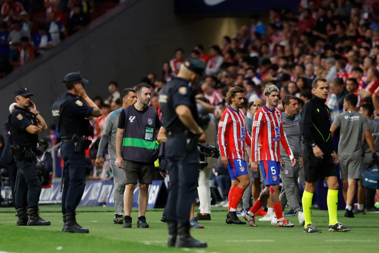 El delantero francés #07 del Atlético de Madrid, Antoine Griezmann, y el mediocampista argentino #05 del Atlético de Madrid, Rodrigo De Paul, abandonan el campo después de que los fanáticos del Atlético de Madrid enviaran artículos al campo después del gol del Atlético de Madrid. El defensor brasileño #03 Eder Militão durante el partido de fútbol de la liga española entre Club Atlético de Madrid y Real Madrid CF en el estadio Metropolitano de Madrid el 29 de septiembre de 2024. (Foto de OSCAR DEL POZO/AFP)