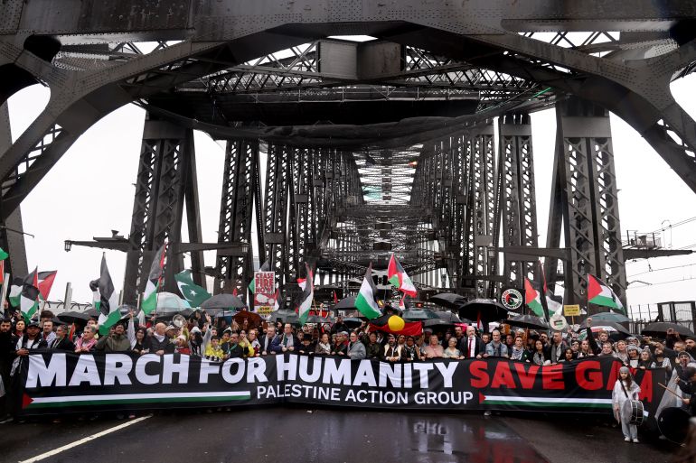 La gente marca detrás de una pancarta que dice March for Humanity Save Gaza en un puente