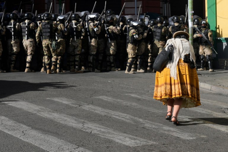 Una mujer pasa junto a un grupo de policías fuertemente armados.