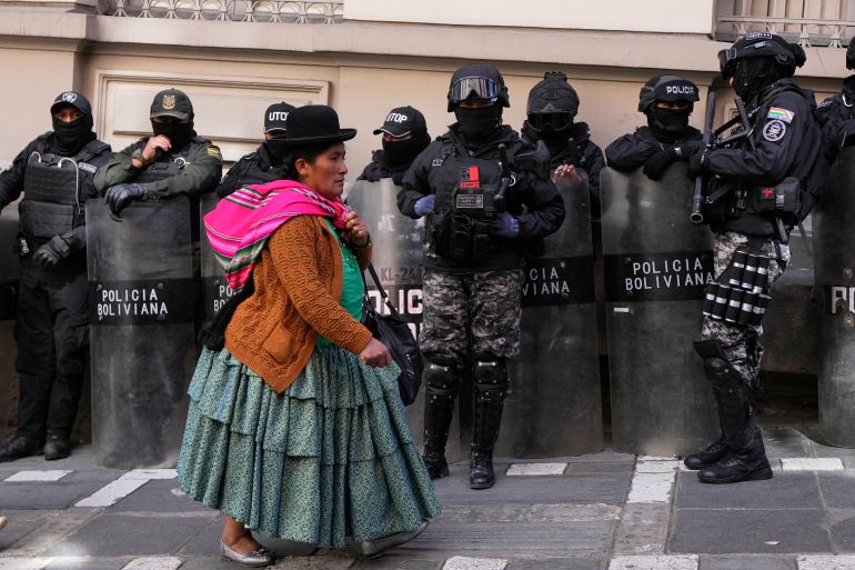 Una mujer indígena en Bolivia pasa a través de la policía en equipos antidisturbios