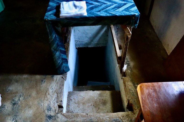 La entrada a un refugio antiaéreo en un hospital clandestino en Kayah.  Está debajo de una mesa.  con escalones estrechos y empinados que conducen al subsuelo.